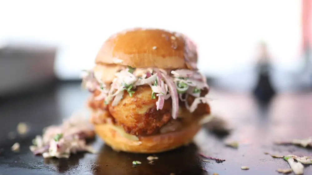 A buttermilk fried chicken burger topped with fennel slaw in a brioche bun