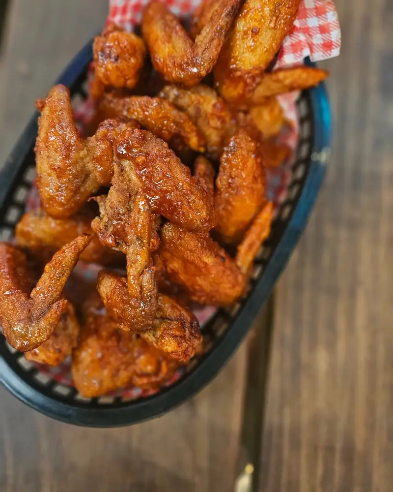A basket of glazed hot wings lined with gingham paper