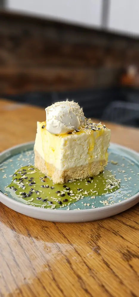 A square of lemon cheesecake in a passionfruit coulis, topped with cream