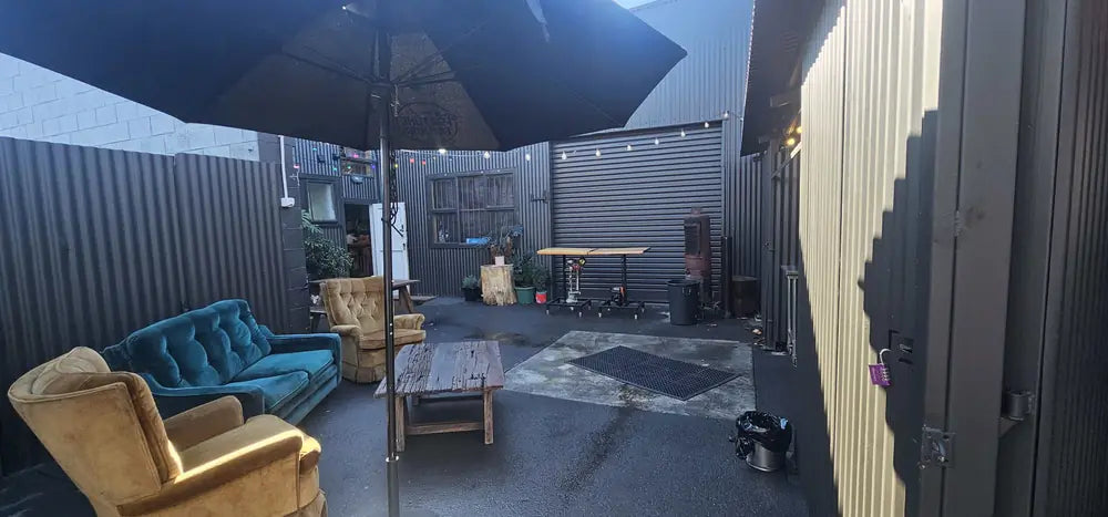 Velvet sofas and a table under a large umbrella in the Peacock Lounge courtyard