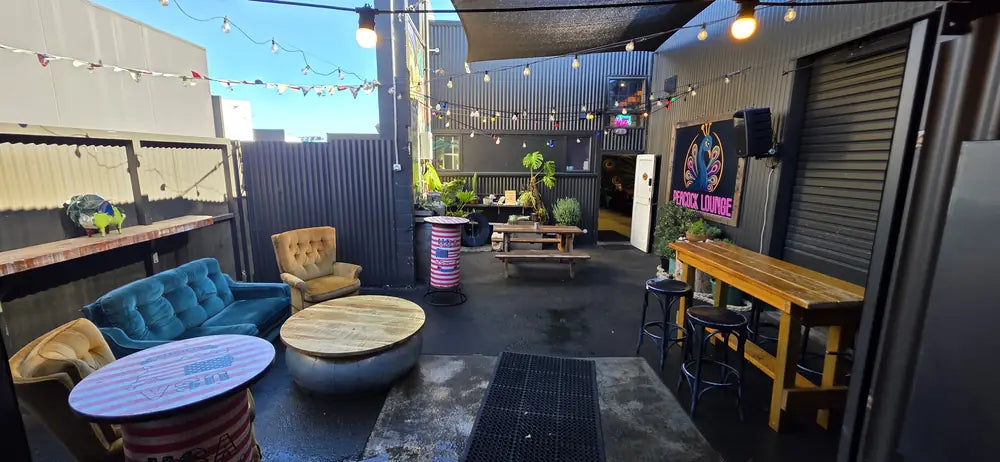 Festoon lights over the Peacock Lounge courtyard at dusk, with sofas and bench seating set out