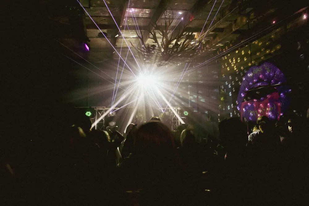 A crowd silhouetted against a starburst of stage lights in the Peacock Lounge
