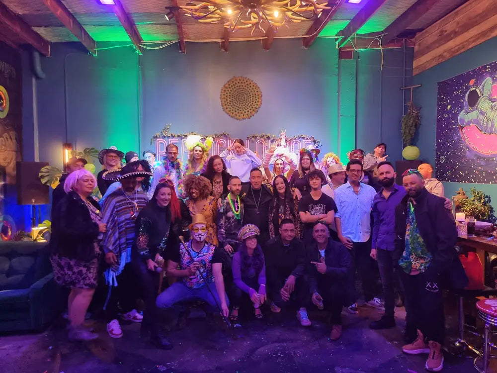 A large group photographed together in the Peacock Lounge under green and purple lighting