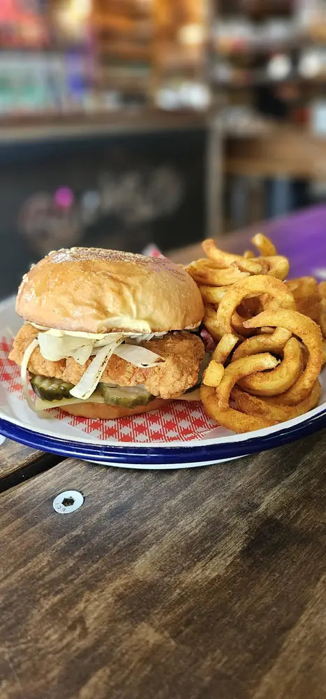 A pulled pork slider with pickles and a pile of curly fries on an enamel plate