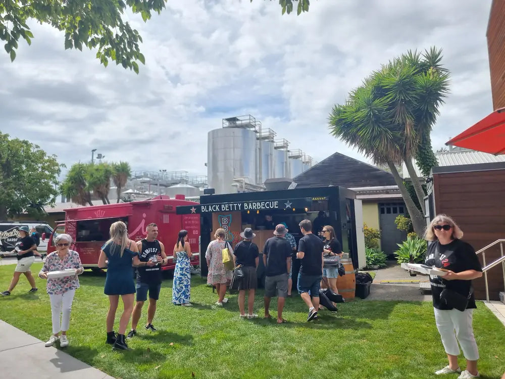 Guests queueing at the Black Betty Barbecue truck on the lawn at a brewery event